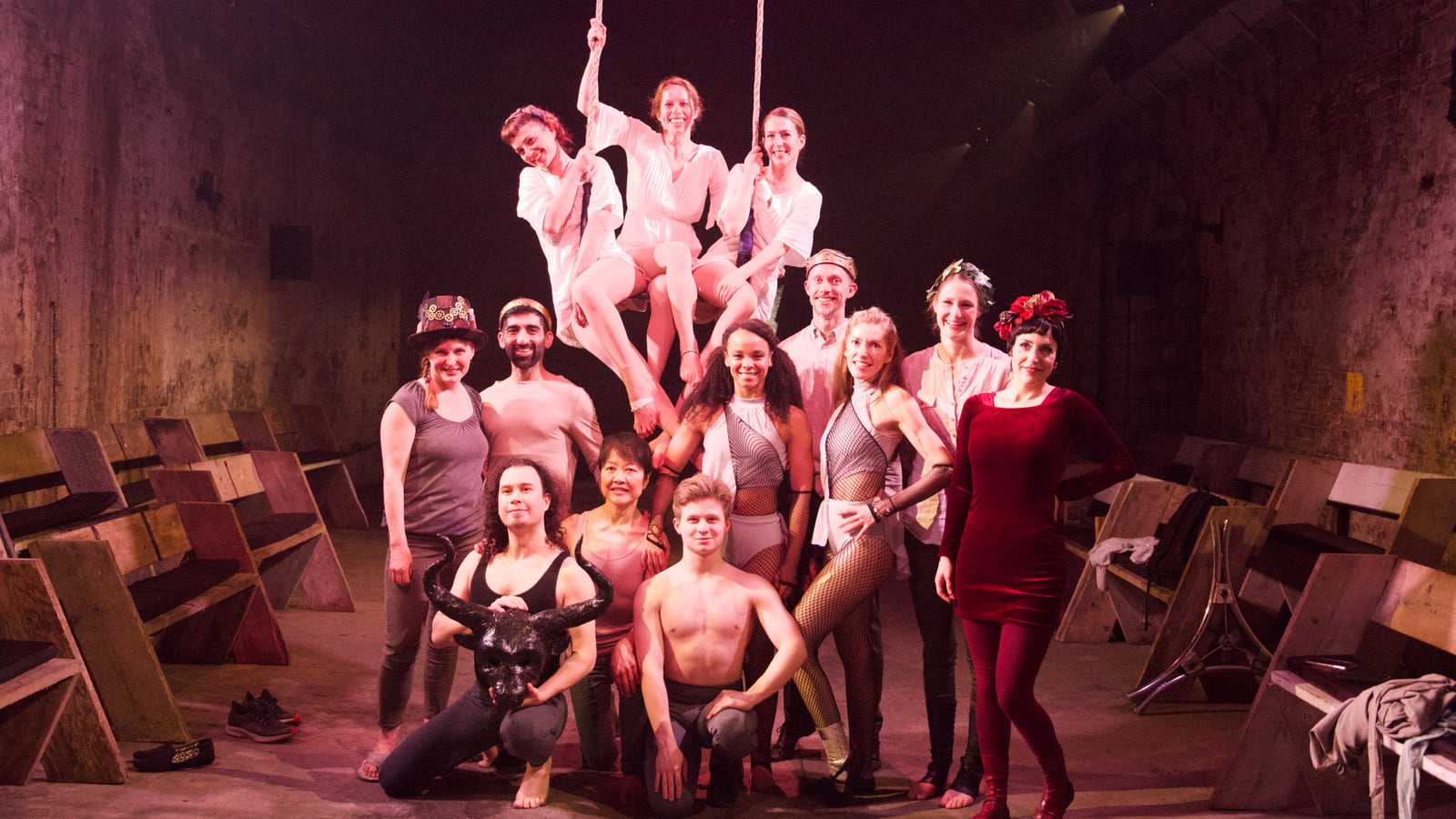 Don't Look Back company: full cast in the vaults, three aerialists on trapeze above, Minotaur mask in the front row