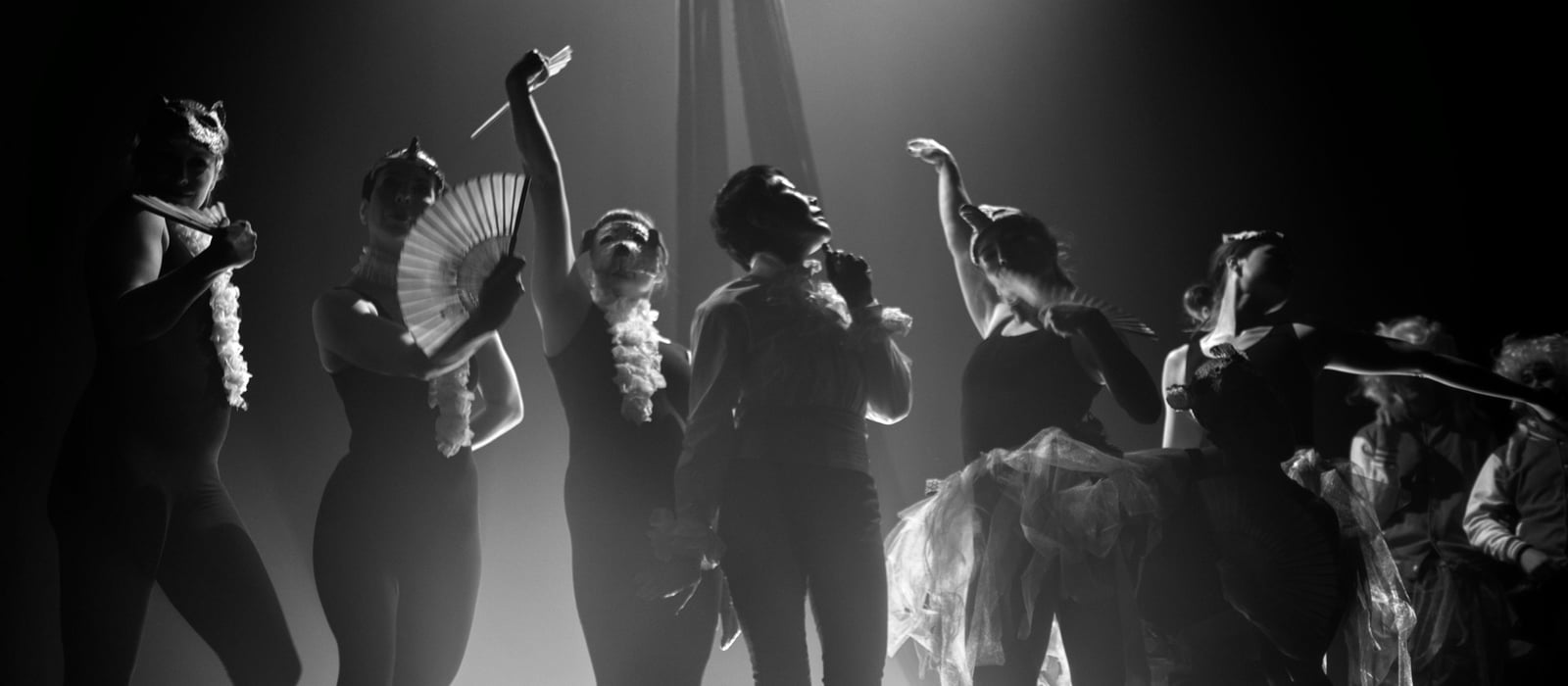 Cast silhouetted under overhead spotlights at Jacksons Lane, with animal masks, fans and a hanging silk