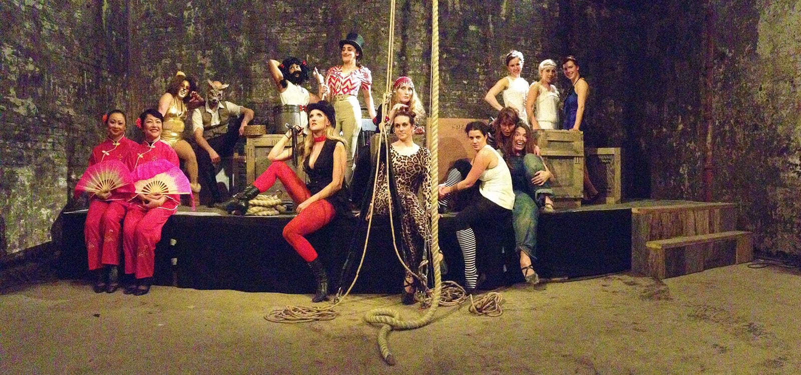 The full Lost Circus cast spread across a low stage in the vaults, with ropes, crates and costume characters